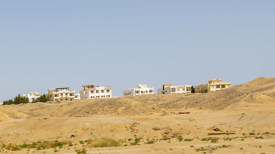 Buildings on desert against clear sky