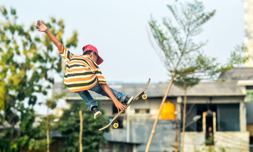 Low angle view of boy skateboarding against sky