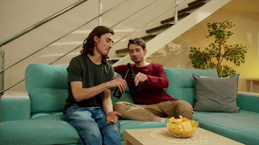 Gay couple sitting on sofa at home