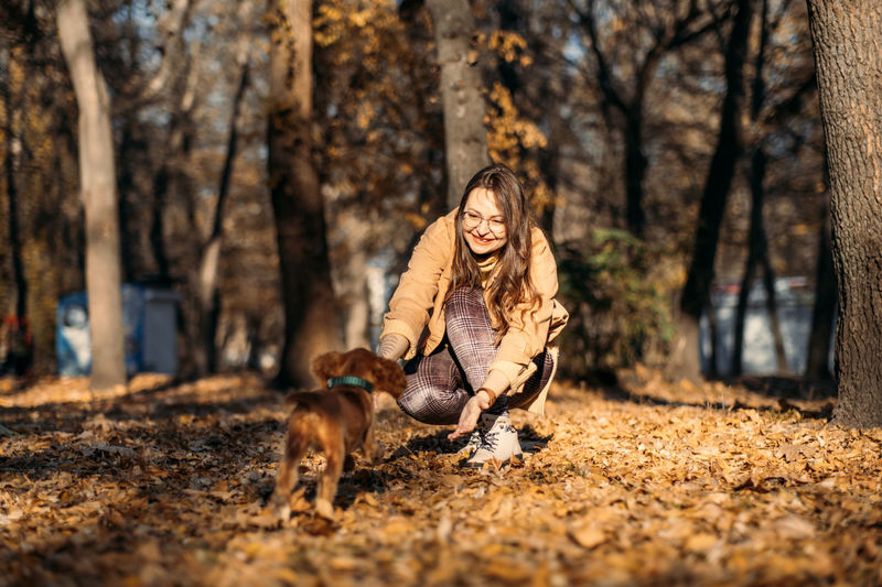Side view of young woman with dog standing in forest