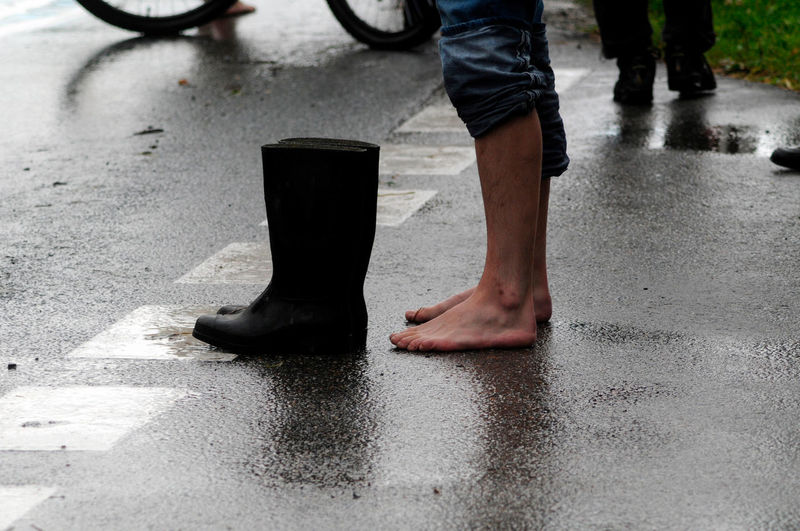 Low section of man standing on wet street
