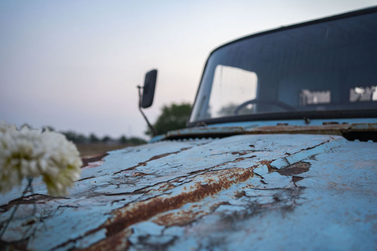 Close-up of rusty car against sky during winter