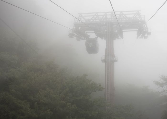 Low angle view of overhead cable car against sky during foggy weather