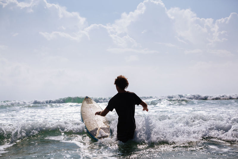 Rear view of man with surfboard in sea