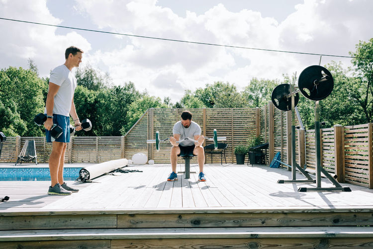 Two friends working out together at their home by the pool home gym
