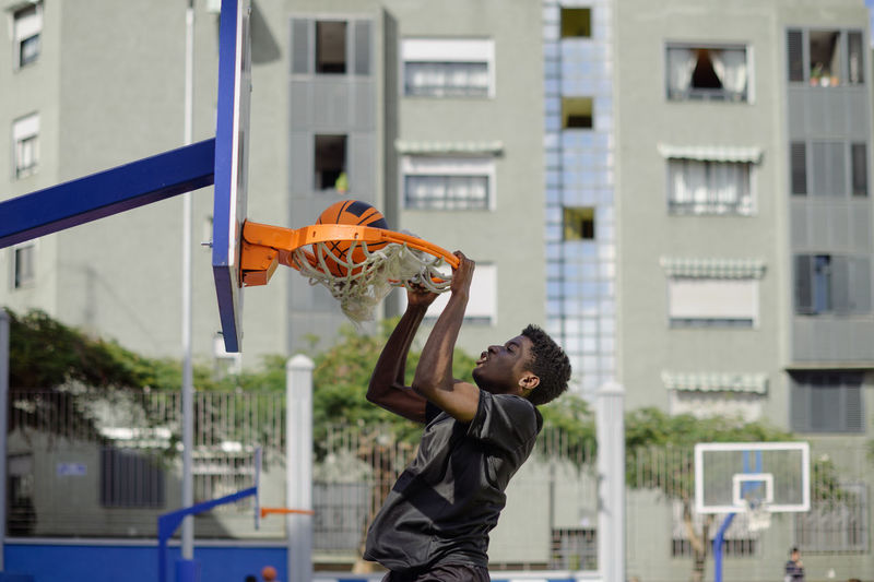 Low angle view of man playing basketball in city