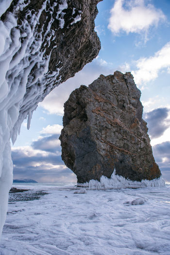 Rock formation on frozen sea against sky
