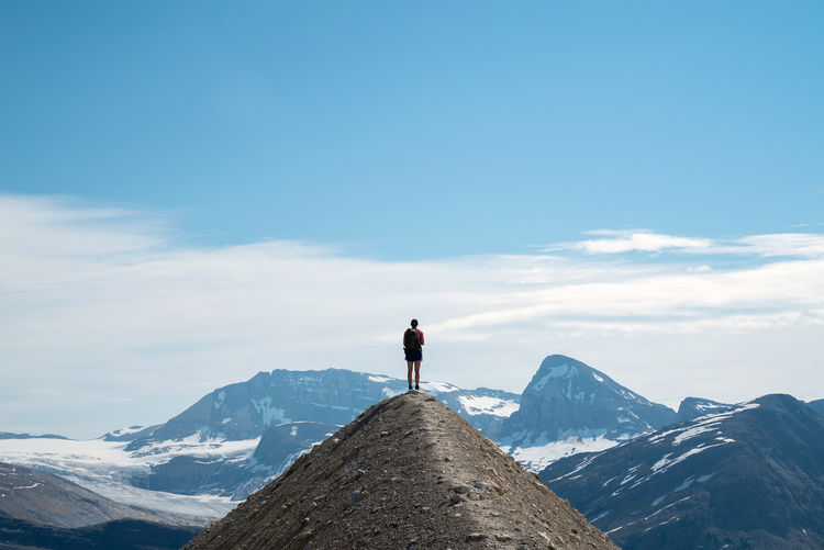 Rear view of man standing on mountain against sky