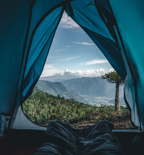 Low section of person relaxing in tent against mountains