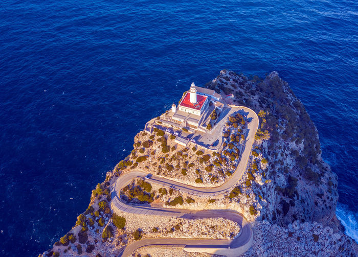 Aerial view of lighthouse on cliff by sea
