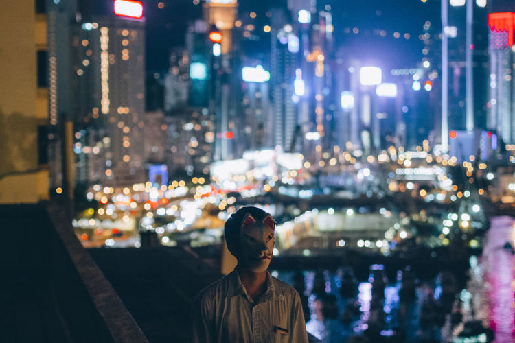 Man wearing mask while standing on city at night