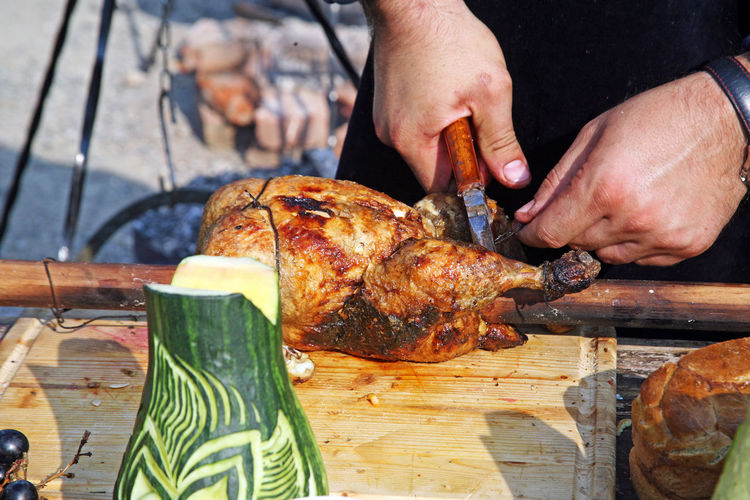 Close-up of man cutting cooked chicken
