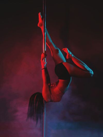 Sensuous woman performing pole dance at nightclub