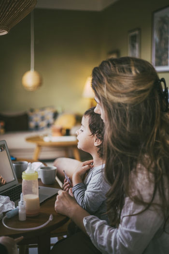 Mother with son taking online advice from doctor on video call at home