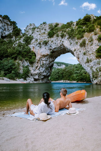 Rear view of friends sitting on shore