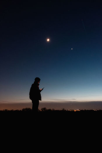 Silhouette man standing on field against sky at night