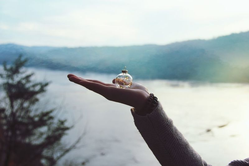 Close-up of hand holding bauble against lake