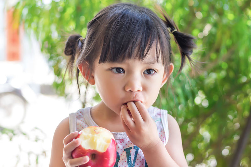 Cute girl eating apple outdoors