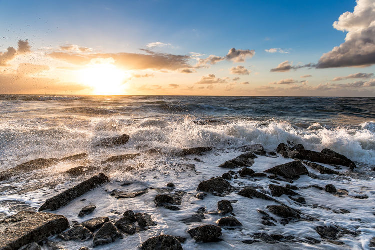 Scenic view of wavy sea at sunset