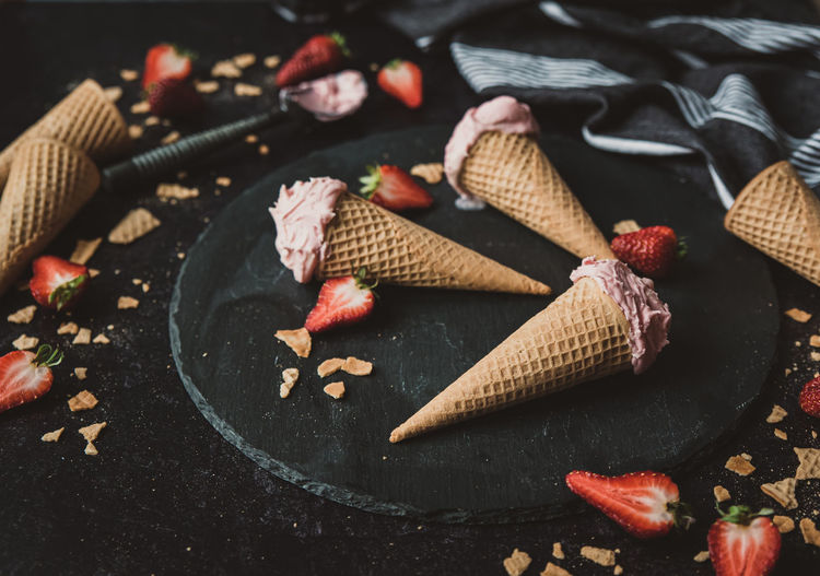 Close up of strawberry ice cream cones on a black background.