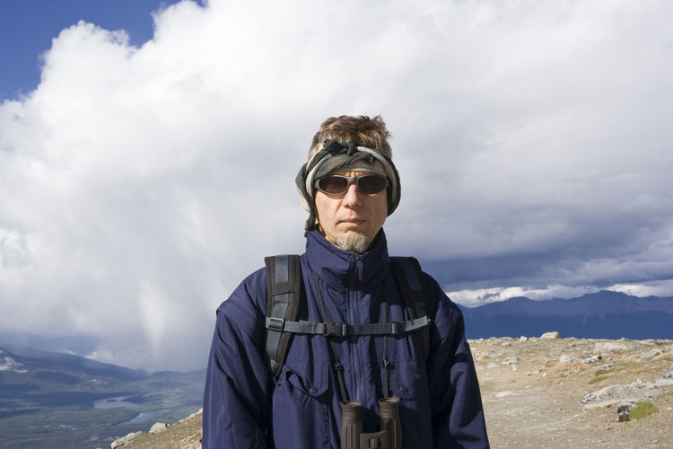 Portrait of with sunglasses hiking at jasper national park against cloudy sky