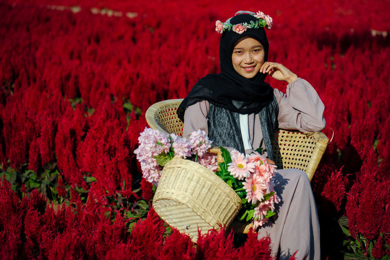 Portrait of a smiling young woman with red flower