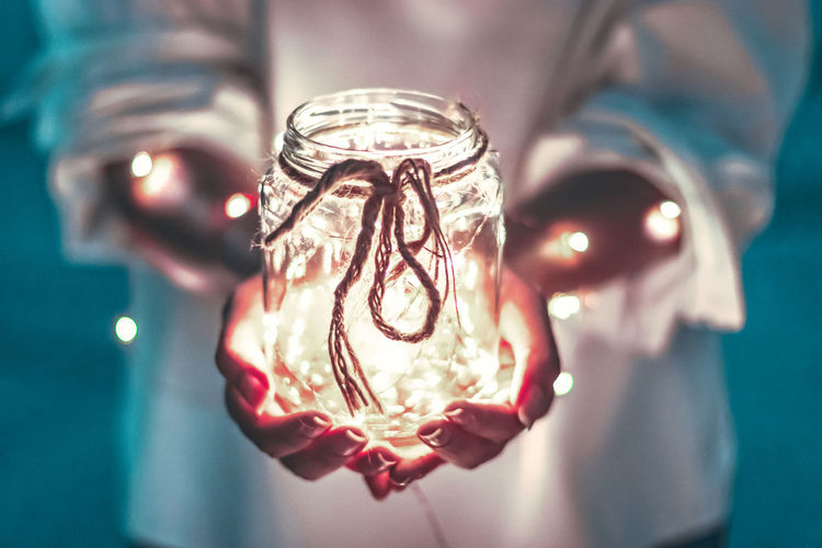 Close-up of hand holding illuminated glass