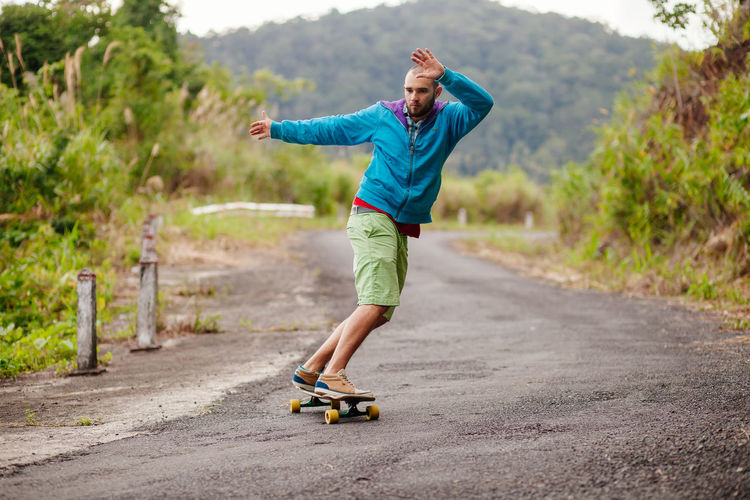 Man skateboarding on road against mountain