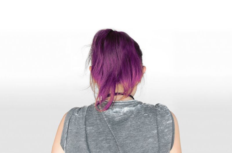 Rear view of young woman with dyed hair against white background