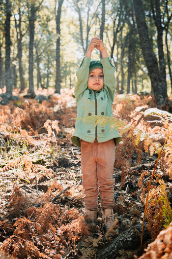 Full length of child standing by tree in forest