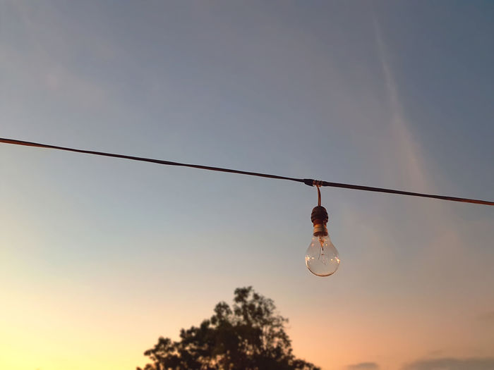 Low angle view of light bulb against sky during sunset