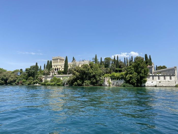 Scenic view of lake by buildings against clear blue sky