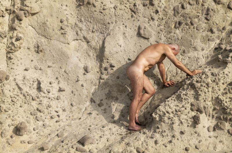 High angle view of shirtless man lying on sand