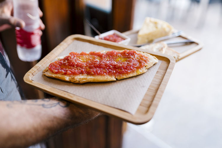 Cropped image of hand holding pizza on table