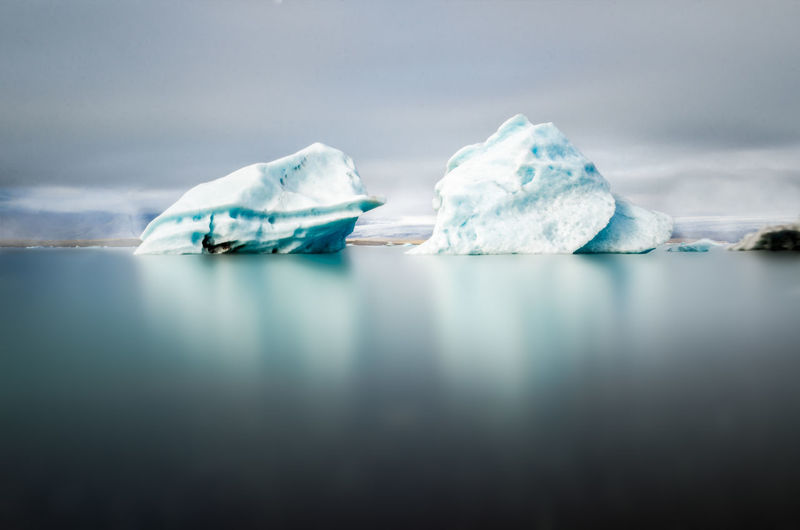 Scenic view of icebergs in sea against sky