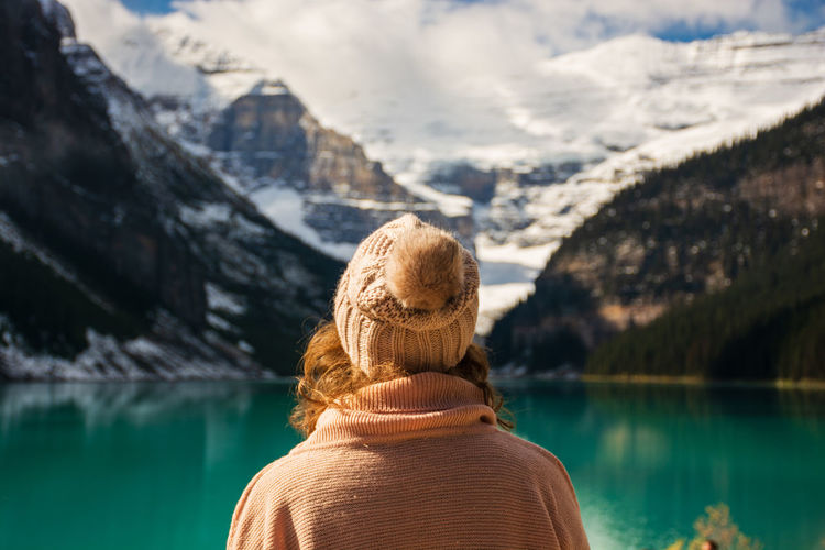 Rear view of woman looking at lake against mountains