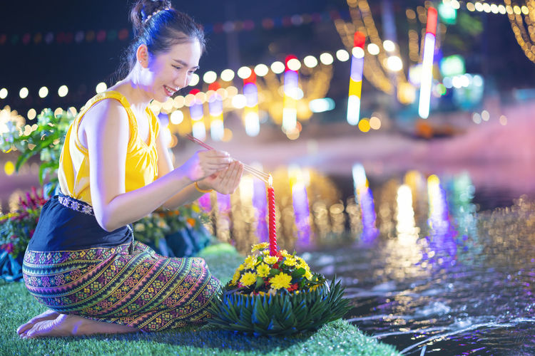 Rear view of woman holding christmas tree at night