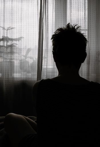 Rear of woman sitting in darkroom at home