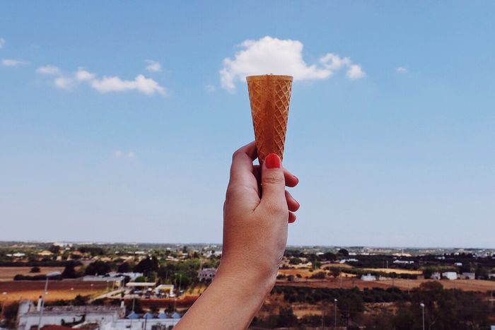 Optical illusion of woman holing clouds on ice cream cone