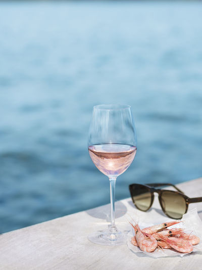 Wine glass on table against sea