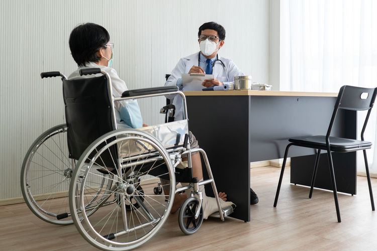 Doctor wearing mask sitting with patient in clinic