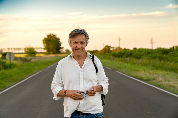 Portrait of man standing on road against sky