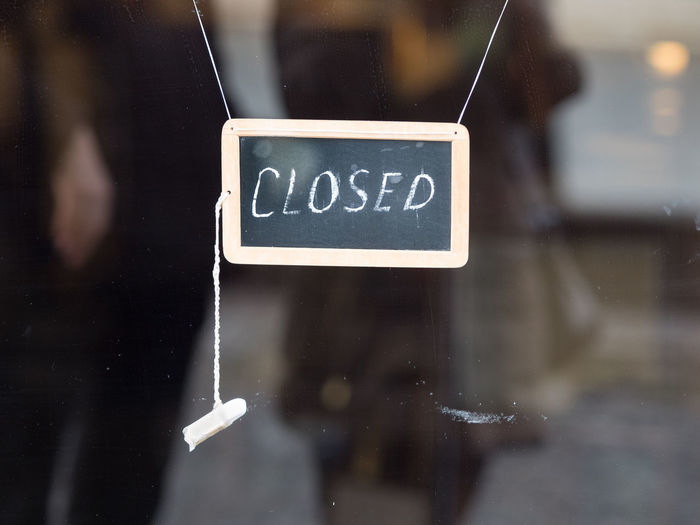Close-up of closed text on blackboard hanging at store