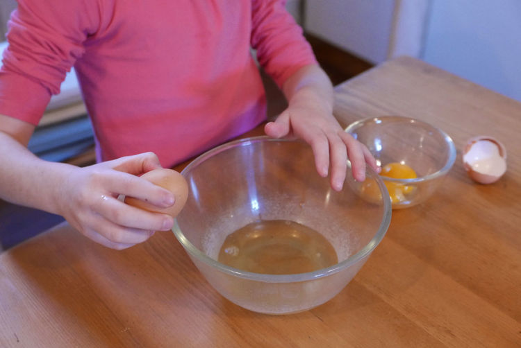Close-up of girl separating yolk and egg on table