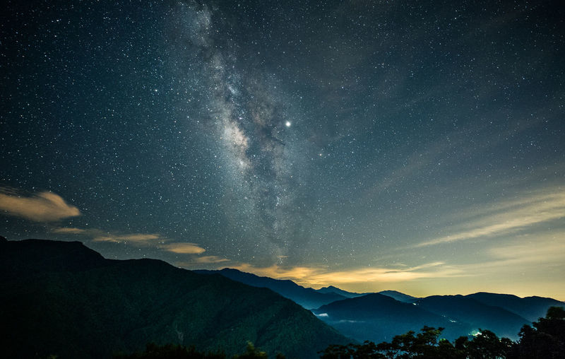 SCENIC VIEW OF MOUNTAINS AGAINST STAR FIELD