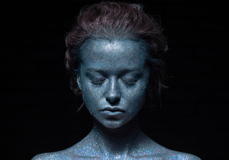 Portrait of a woman with a blue face in glitter