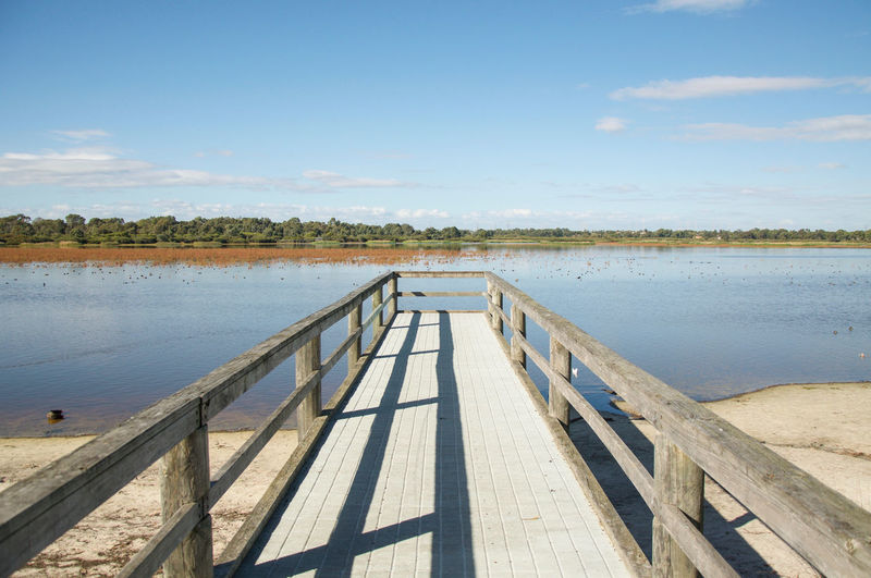 Boardwalk over lake against sky