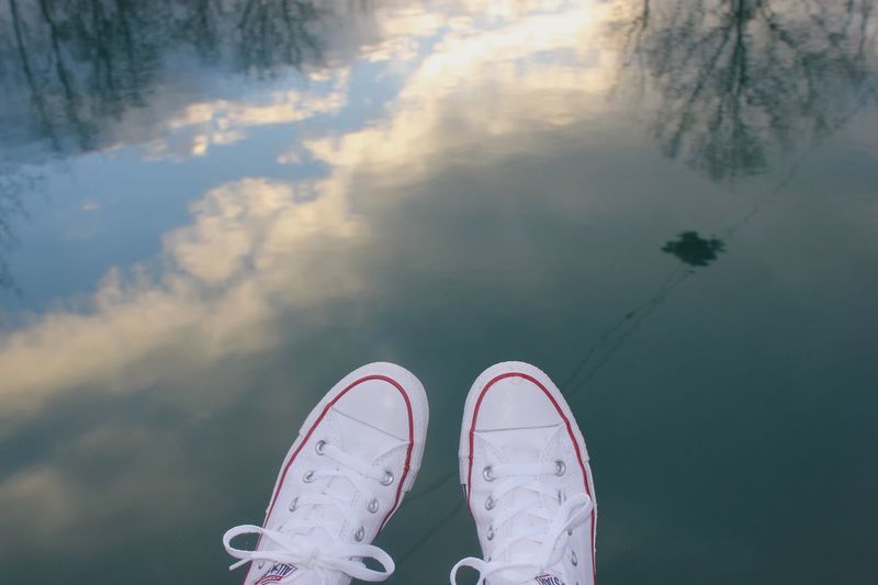 Low section of person wearing shoes over lake