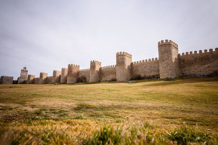 View of fort of the medieval wall un Ávila on field against sky