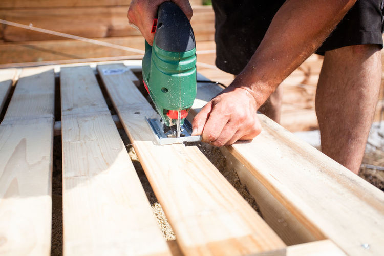 Midsection of carpenter using machinery while making furniture